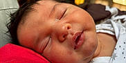 Shane is registered to the contest to win money with this photo: baby, sleeping, close_up, face, chubby_cheeks, infant, white_clothing, stars_pattern, red_fabric, peaceful, resting, portrait, soft_lighting, indoor, newborn, cute, skin, head, mouth, eyelashes