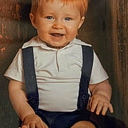 Maélyo a rejoint le concours — aidez-le/la à gagner de superbes lots ! baby, child, smiling, red_hair, blue_eyes, white_shirt, suspenders, wooden_box, feet, toes, happy, portrait, cute, infant, sitting, chubby_legs, indoors, closeup, hands, playful
