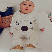 Judith participe au concours pour gagner de l'argent avec cette photo : baby, infant, child, cute, smiling, blue_eyes, white_clothing, bear_sweater, hat, shoes, tattoo, changing_table, nursery, indoor, person, face, portrait, sitting, cozy, adorable