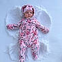 baby, snow, snow_angel, pink_snowsuit, floral_pattern, hood, hat, cold_weather, winter, outdoor, infant, face, cute, lying_down, frost, child, warm_clothing, footwear, nature, play