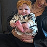 baby, child, woman, headband, mickey_mouse, clothing, couch, smile, happy, holding, indoor, portrait, person, black_jacket, hand, foot, cute, infant, casual, seated