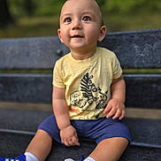 Devin is registered to the contest to win money with this photo: toddler, child, bench, outdoor, smiling, yellow_tshirt, blue_shoes, shorts, nature, park, happy, sitting, cute, face, person, footwear, casual_clothing, daylight, expression, young_child