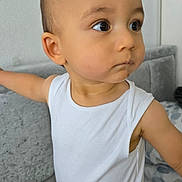 Devin joined the competition — help win amazing prizes! toddler, child, white_shirt, indoor, sofa, couch, pillow, curious, portrait, face, arm, skin, young_child, looking_away, home, casual, sleeveless_shirt, furniture, expression, young