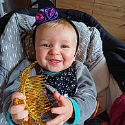 Tahys a rejoint le concours — aidez-le/la à gagner de superbes lots ! baby, smiling, child, hat, headwear, comb, golden, hand, clothing, bib, seat, cushion, indoor, kitchen, wood_cabinet, refrigerator, toy, happy, face, person