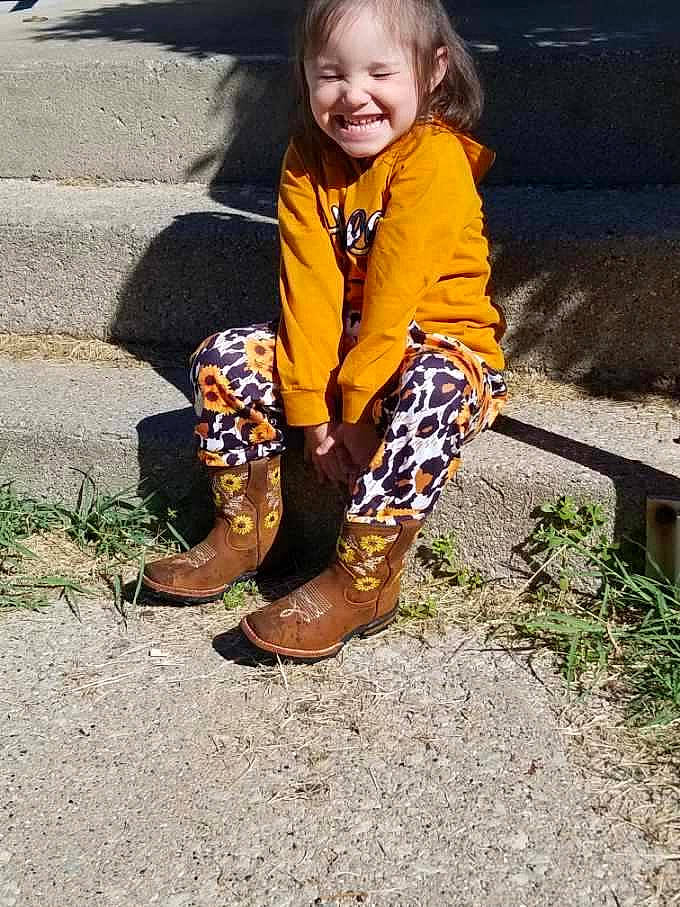 Gabbriella joined the competition — help win amazing prizes! asphalt, eye, face, foot, fun, grass, happy, human_body, human_leg, jacket, joy, leg, leisure, people_in_nature, person, road_surface, sitting, smile, sneakers, soil