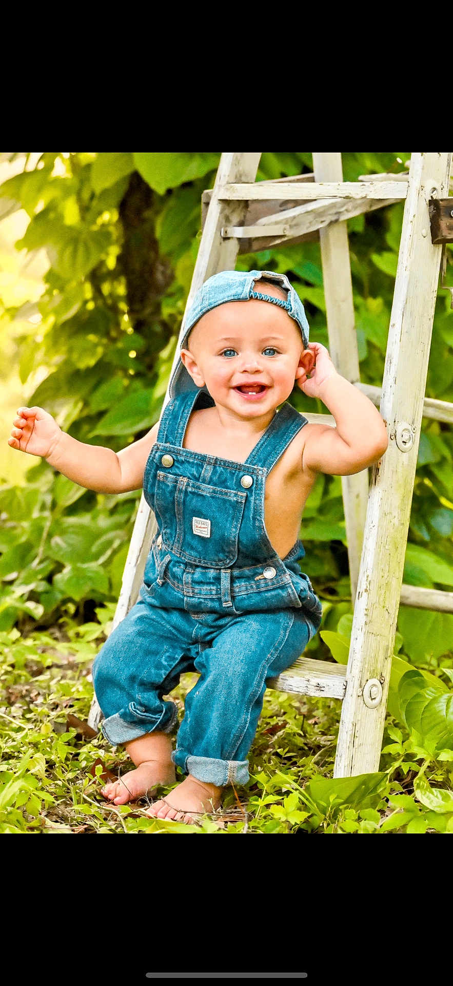 Lex joined the competition — help win amazing prizes! toddler, child, smiling, denim_overalls, cap, barefoot, ladder, greenery, outdoor, grass, happy, cute, baby, nature, portrait, sitting, blue_eyes, summer, casual_clothing, sunlight