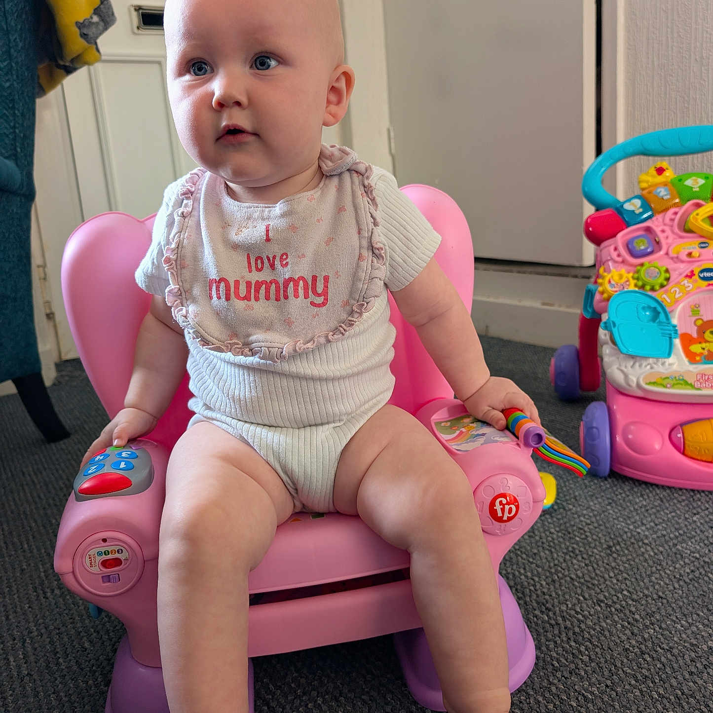 Maeve joined the competition — help win amazing prizes! baby, bib, carpet, child, clothing, colorful, cute, expression, foot, hand, home, indoor, infant, person, pink_chair, play, sitting, toy, walker, young