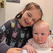 Daisy-May joined the competition — help win amazing prizes! child, baby, smiling, happy, indoor, sweatshirt, bubble_tea_print, cute, affection, portrait, person, face, hand, baby_clothes, curious, holding, white_surface, family, siblings, together