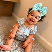Liliana joined the competition — help win amazing prizes! baby, child, infant, smiling, happy, portrait, indoor, carpet, floor, bow, headband, dress, sitting, curly_hair, brown_hair, face, eyes, feet, home, photography