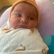 Alfonso Angelo is registered to the contest to win money with this photo: baby, infant, swaddled, blanket, hat, orange_hat, elephant_pattern, newborn, face, cute, indoors, nursery, soft_light, portrait, child, cozy, sleepy, small, wrapped, curious