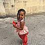 Daya a rejoint le concours — aidez-le/la à gagner de superbes lots ! child, smiling, braids, beads, floral_top, pants, sandals, outdoor, concrete, wall, joyful, cute, standing, playful, person, young, happy, fashion, portrait, daylight