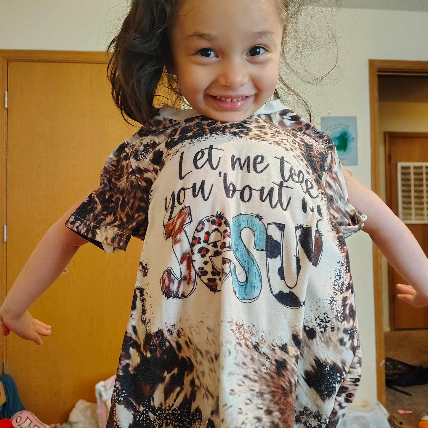 Jaylee is registered to the contest to win money with this photo: child, smiling, indoor, tshirt, animal_print, text, long_hair, messy_hair, playful, door, carpet, room, clothing, person, happy, home, casual, young, portrait, cute