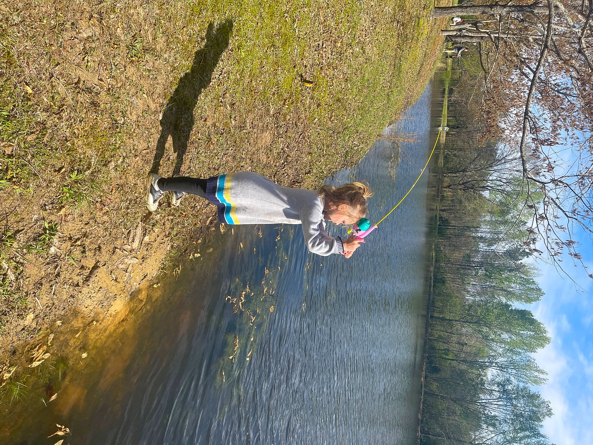 Alyson is registered to the contest to win money with this photo: adventure, biome, fun, grass, lake, landscape, leisure, people_in_nature, person, plant, recreation, reflection, rope, shadow, sky, slope, soil, toddler, tree, water