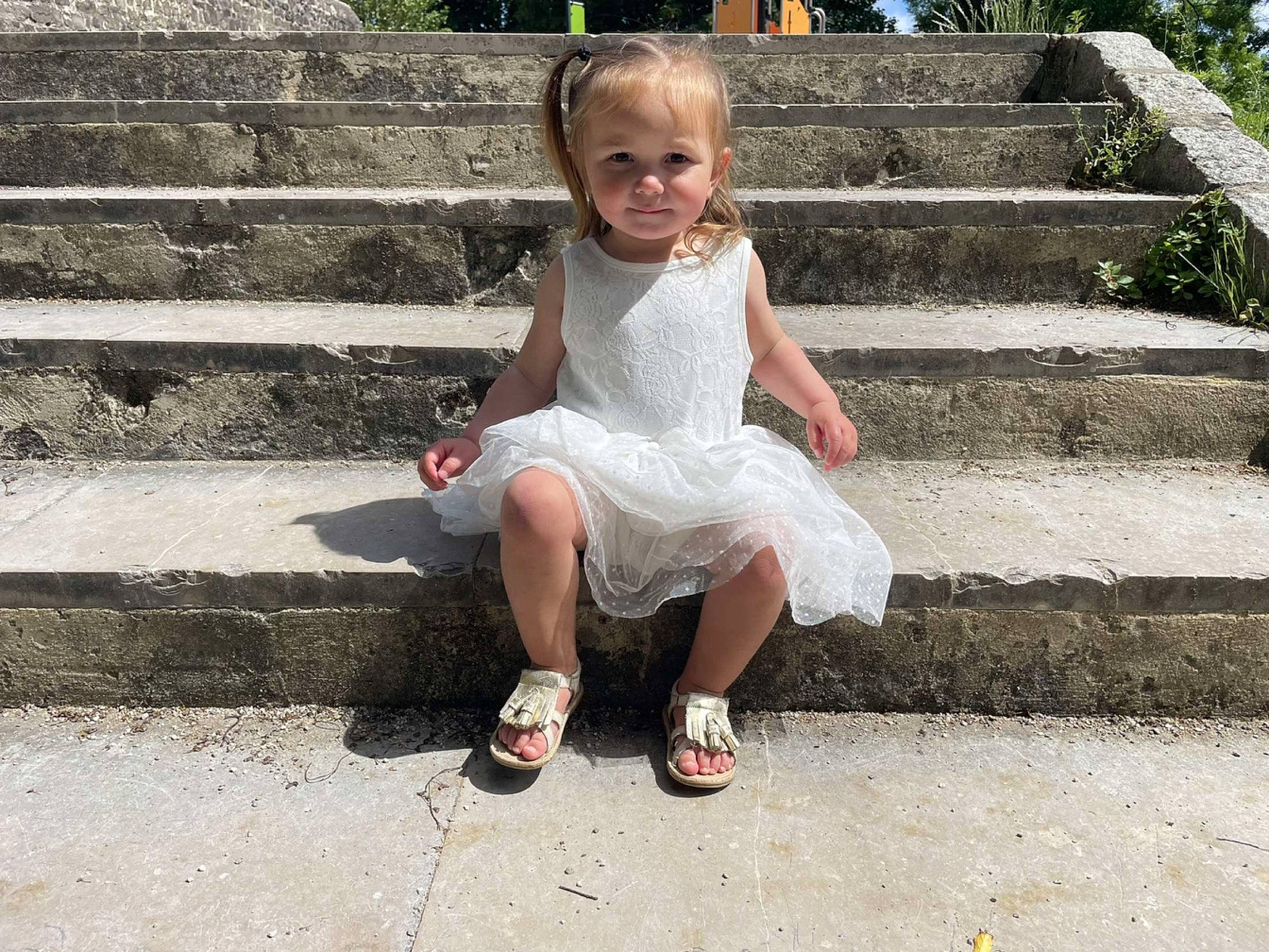 Maëlia participe au concours pour gagner de l'argent avec cette photo : asphalt, child, day_dress, foot, fun, grass, happy, human_leg, leg, leisure, pattern, people_in_nature, person, plant, road_surface, sandal, sidewalk, sitting, stairs, toddler