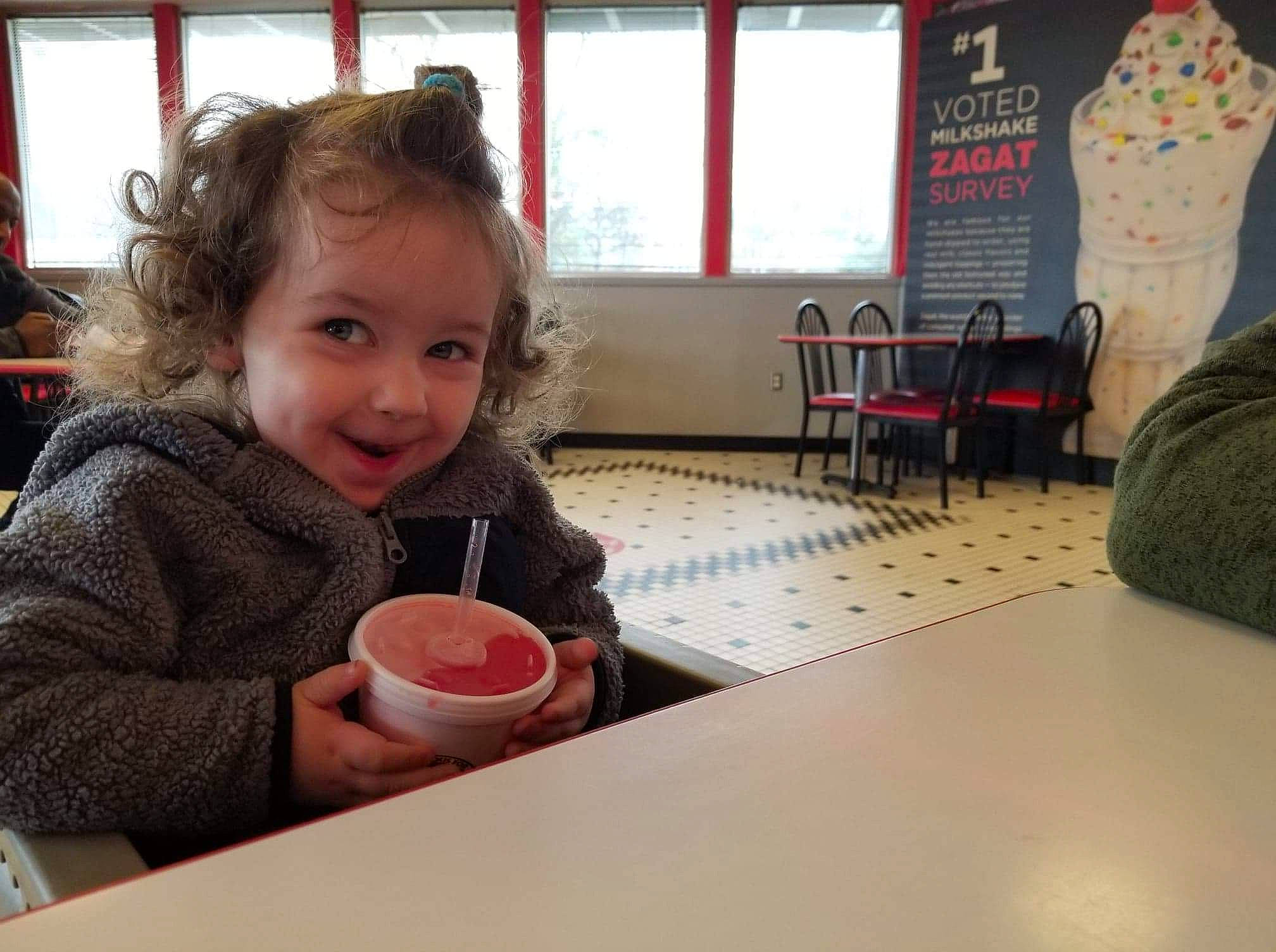 Gordon is registered to the contest to win money with this photo: breakfast, chair, child, drink, drinkware, event, flooring, fun, happy, joy, leisure, person, room, sharing, sitting, smile, t_shirt, table, tableware, toddler