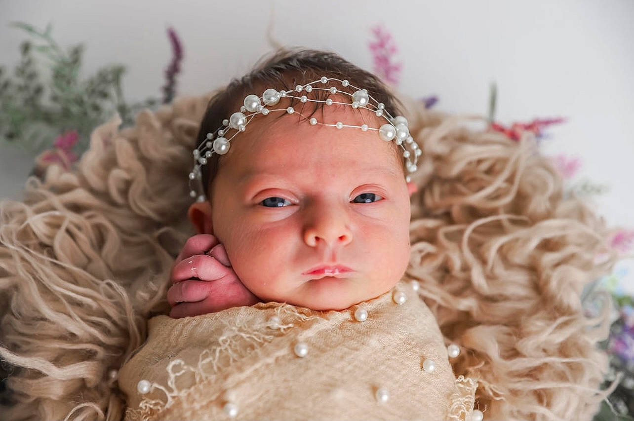 Jersey is registered to the contest to win money with this photo: baby, bridal_accessory, child, embellishment, eye, eyebrow, eyelash, face, flash_photography, grass, happy, headband, headgear, headpiece, headwear, iris, jewellery, person, pink, skin