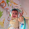 Elijah is registered to the contest to win money with this photo: baby, smiling, infant, play_mat, blanket, animal_print, cute, happy, indoors, child, onesie, reaching, colorful, soft_toys, cheerful, person, portrait, baby_toys, lying_down, bright