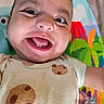 baby, smiling, close_up, onesie, cookie_pattern, play_mat, colorful, child, portrait, happy, face, infant, cute, indoor, bright, young_child, expression, clothing, skin, head