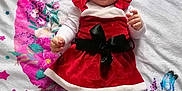 Manon a rejoint le concours — aidez-le/la à gagner de superbes lots ! baby, smiling, red_dress, white_tights, santa_hat, blanket, floral_pattern, butterflies, lying_down, happy, infant, holiday, festive, cute, child, portrait, clothing, soft_texture, fabric, indoor
