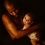 Ella a rejoint le concours — aidez-le/la à gagner de superbes lots ! man, baby, child, portrait, intimacy, love, family, skin, barechest, holding, darkbackground, warmlighting, closeup, father, parent, infant, expression, candid, tenderness, affection