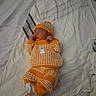 Jayden joined the competition — help win amazing prizes! newborn, baby, infant, sleeping, bed, blanket, knitted_outfit, orange_clothing, hat, mittens, socks, portrait, indoors, cozy, lying_down, peaceful, text_overlay, date, bedding, photograph
