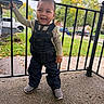child, toddler, boy, smiling, standing, outdoor, porch, railing, overalls, denim, shirt, sneakers, autumn, leaves, neighborhood, street, cars, portrait, daylight, happy