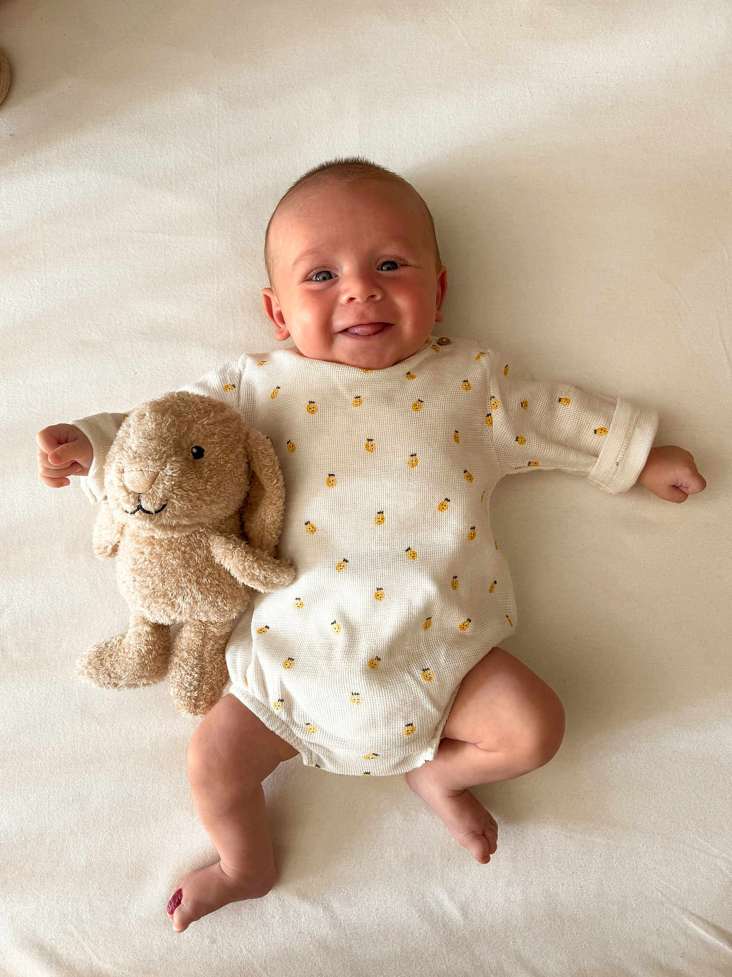 Paul participe au concours pour gagner de l'argent avec cette photo : baby, smiling, infant, stuffed_animal, bunny, toy, onesie, pattern, bee, blanket, lying_down, cute, happy, child, face, skin, soft, indoor, portrait, playful