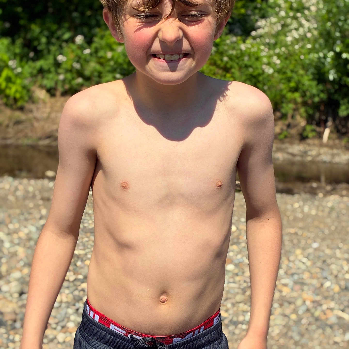 Declan is registered to the contest to win money with this photo: boy, child, shirtless, outdoor, sunlight, nature, greenery, rocks, summer, smile, face, hair, shorts, skin, person, young, happy, casual, daylight, portrait
