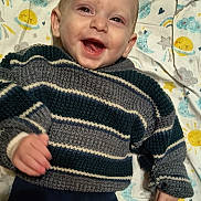 Coleson joined the competition — help win amazing prizes! baby, smiling, sweater, striped, blanket, sun, moon, stars, clouds, happy, infant, child, portrait, lying_down, cute, warm_clothing, indoors, colorful, patterned, face