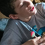 Tatum is registered to the contest to win money with this photo: child, boy, lollipop, candy, gray_shirt, indoor, light, face, hand, playful, young, casual, smile, portrait, person, food, snack, fun, relaxed, cute