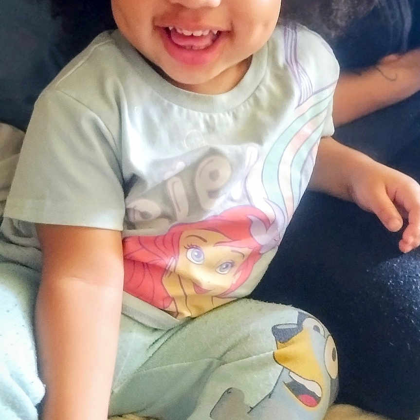 Wynter is registered to the contest to win money with this photo: afro_hair, bed, blanket, cartoon_print, casual, child, cozy, cute, foot, hand, happy, indoor, laughing, pajamas, person, portrait, skin, smiling, soft_lighting, toddler