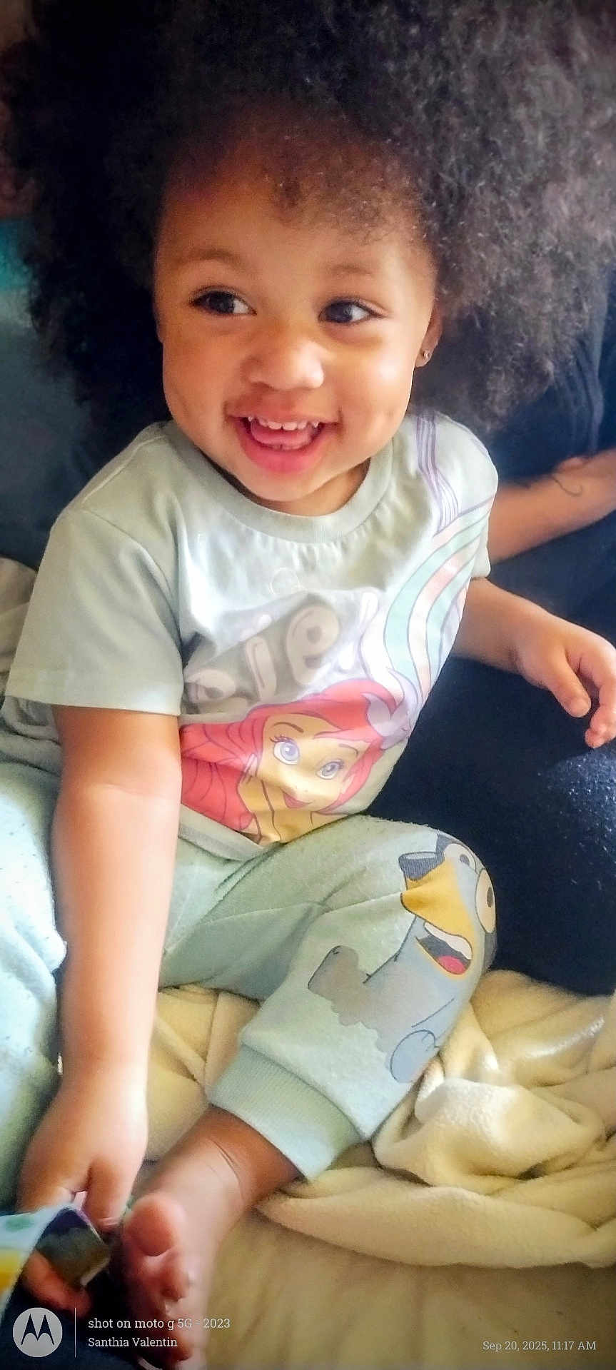 Wynter is registered to the contest to win money with this photo: toddler, child, smiling, laughing, afro_hair, pajamas, cartoon_print, bed, blanket, indoor, happy, cute, person, skin, hand, foot, cozy, soft_lighting, portrait, casual