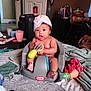 baby, child, infant, toy, seat, little_tikes, hat, indoor, blanket, cup, furniture, clothing, floor, table, snack, bag, room, face, person, expression