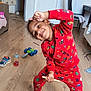 bottle, chair, child, curtains, floor, furniture, happy, indoors, kid, living_room, pajamas, person, playful, red_clothing, shoe, smiling, socks, table, toy_car, wooden_floor