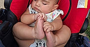 Zeldalyn is registered to the contest to win money with this photo: baby, sleeping, stroller, red, black, onesie, infant, child, cute, peaceful, hand, foot, outdoor, cartoon_print, seat, rest, skin, head, closed_eyes, young