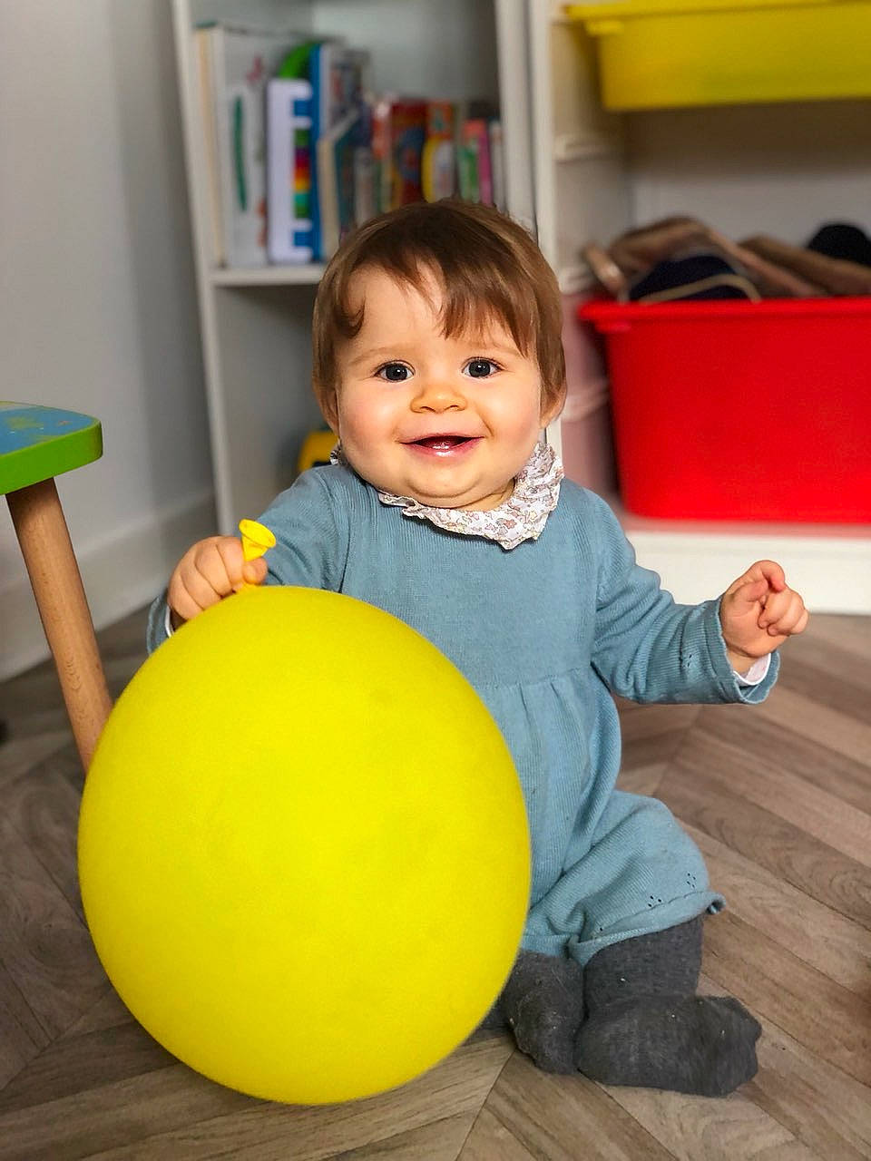 Léa a rejoint le concours — aidez-le/la à gagner de superbes lots ! baby_playing_with_toys, baby_toddler_clothing, ball, bookcase, child, clothing, face, facial_expression, finger, floor, flooring, fun, happy, joy, person, shelf, sitting, smile, standing, toddler