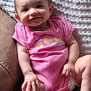 Savannah joined the competition — help win amazing prizes! baby, child, smiling, pink_onesie, flower_print, chair, leather, blanket, happy, cute, infant, portrait, sitting, hand, face, skin, comfort, indoor, young, person