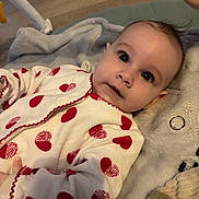 Théa participe au concours pour gagner de l'argent avec cette photo : baby, infant, onesie, hearts, red, white, blanket, soft_toy, plush, cute, child, face, portrait, lying_down, cozy, indoors, closeup, wide_eyes, curious, skin