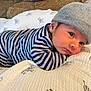 baby, infant, striped_clothing, blue_and_white, beanie, hat, blanket, zebra_pattern, couch, indoor, face, eyes, portrait, cute, child, newborn, resting, cozy, soft, home