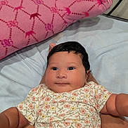 Kiara joined the competition — help win amazing prizes! baby, infant, child, floral_clothing, pink_pillow, bed, legs, person, cute, portrait, indoors, skin, face, smile, lying_down, comfort, young_child, furniture, soft_toy, patterned