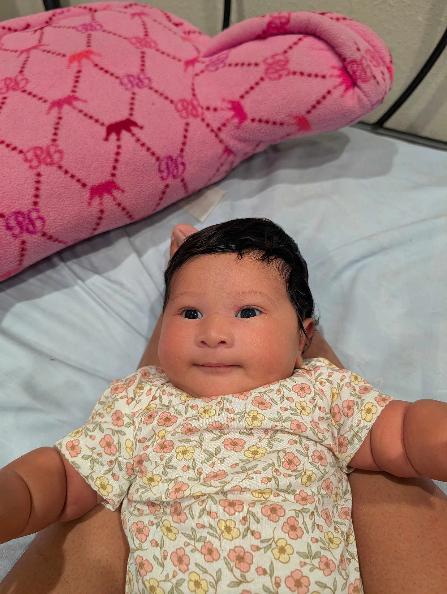 Kiara joined the competition — help win amazing prizes! baby, infant, child, floral_clothing, pink_pillow, bed, legs, person, cute, portrait, indoors, skin, face, smile, lying_down, comfort, young_child, furniture, soft_toy, patterned