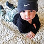 baby, child, beanie, hat, carpet, camo_pants, black_top, lying_down, indoors, curious, blue_eyes, cute, soft_texture, hand, face, portrait, infant, fashion, young_child, floor