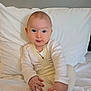 baby, infant, child, white_clothing, sitting, bed, pillow, blanket, indoors, cute, portrait, soft_light, hands, feet, expression, young, cozy, comfort, infant_clothing, face