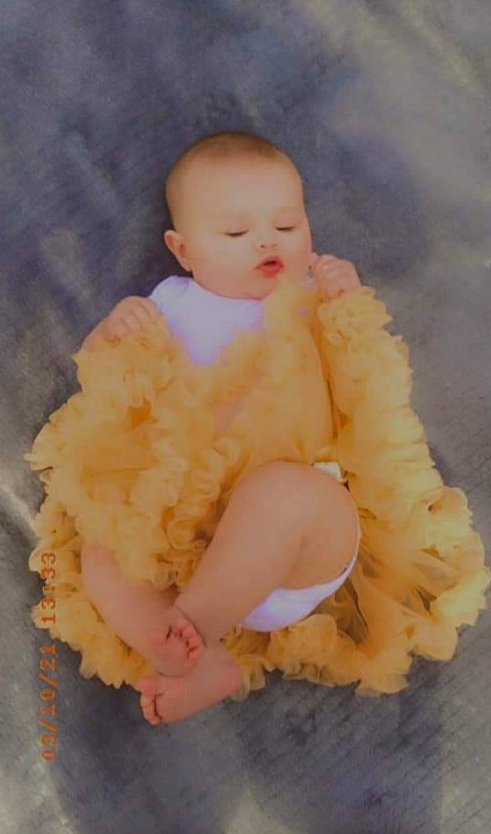 Claudia is registered to the contest to win money with this photo: baby, baby_products, baby_toddler_clothing, comfort, face, fashion_accessory, fun, fur, fur_clothing, happy, head, headgear, linens, peach, person, petal, pink, ruffle, sitting, toddler
