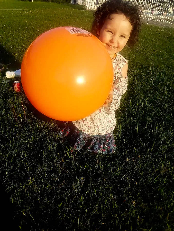Kayla joined the competition — help win amazing prizes! abdomen, ball, balloon, child, flash_photography, fun, gesture, grass, happy, heat, human_leg, joy, leisure, party_supply, people_in_nature, person, recreation, sitting, smile, sphere