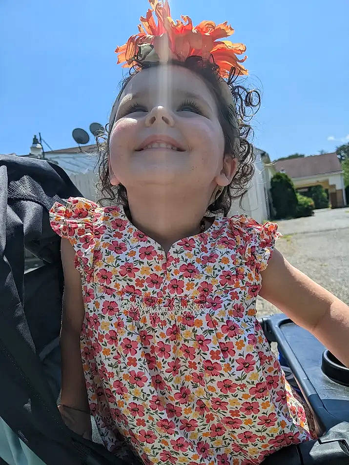 Kayla is registered to the contest to win money with this photo: bag, child, daytime, event, fashion_accessory, flower, fun, happy, headgear, headpiece, leisure, pattern, person, personal_protective_equipment, sky, sleeve, smile, spring, toddler, tourism
