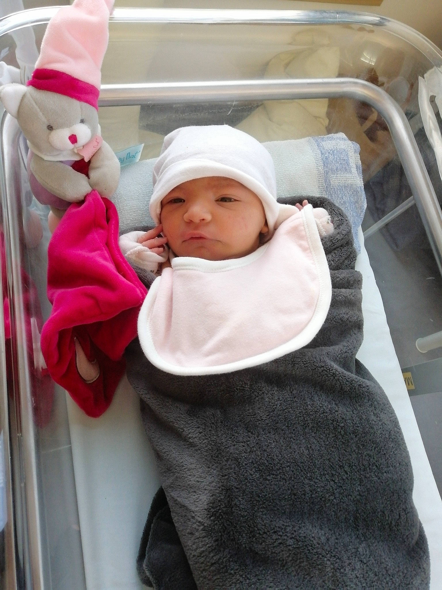 Maëlys participe au concours pour gagner de l'argent avec cette photo : baby, baby_carriage, baby_products, baby_safety, baby_sleeping, baby_toddler_clothing, beanie, cap, child, comfort, headwear, hoodie, linens, person, room, service, sitting, stuffed_toy, toddler, white