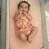 Skyla is registered to the contest to win money with this photo: baby, infant, child, playpen, mattress, pink, watermelon_pattern, clothing, hand, fingers, cute, curious, lying_down, indoors, soft_toys, hair_bow, sleepwear, face, skin, newborn