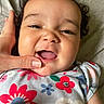 baby, child, smiling, face, hand, curly_hair, infant, closeup, floral_pattern, colorful_clothing, cute, happy, skin, portrait, person, toddler, indoors, human, young, expression