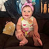 Layken joined the competition — help win amazing prizes! baby, child, infant, pink_headband, fruit_pattern, smiling, sitting, couch, milestone_sign, 8_months, decorative_sign, blanket, indoors, cute, happy, portrait, young_child, headwear, clothing, person